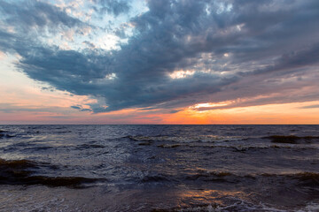 Stormy sea with sunset sky and orange-yellow sun through the clouds over. Meditation at the ocean and sky background. Tranquil seascape. Horizon over the water. Useful for design and place for text.