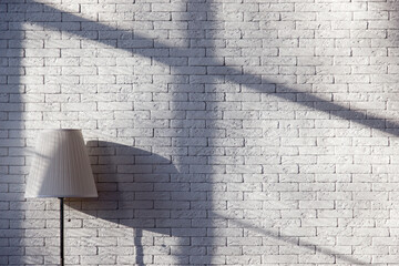 Modern loft living room with high ceiling, empty white brick wall and lamp with shadows on the waall