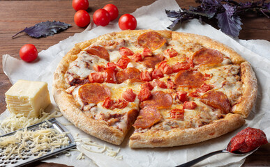 Pepperoni pizza on a wooden table. Pizza with sausage, tomato paste and tomatoes on a wooden table.