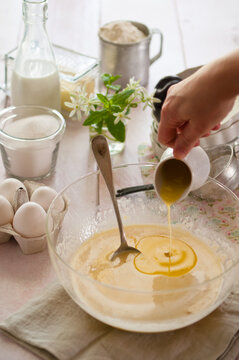 pouring melted butter in a bowl with flour, eggs and milk