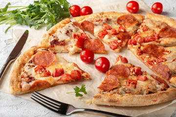 Pepperoni pizza on a light background. Pizza with sausage, tomato paste and tomatoes on a light...