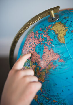 Child points to Canada on a globe