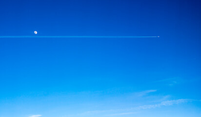 An airplane up in the sky, passing the Moon