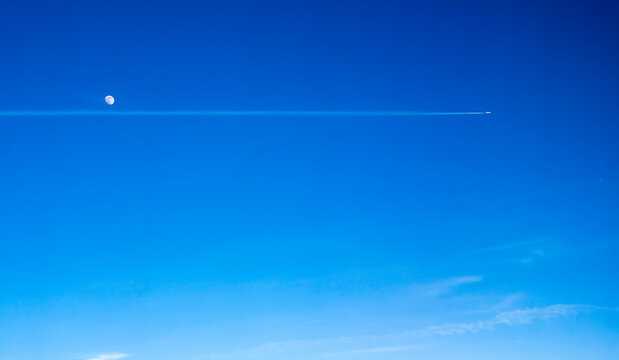 An airplane up in the sky, passing the Moon