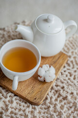 A mug of hot tea, a teapot, a wooden stand on an ottoman. Cozy autumn. Winter breakfast. Cotton.