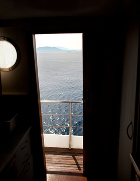 View from a sailboat through a doorpost with sun reflecting on the water.