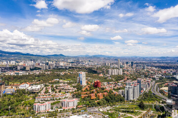 Espectacular vista aérea panorámica de la zona de Santa Fe al poniente de la Ciudad de México con un cielo con muchas nubes como fondo.