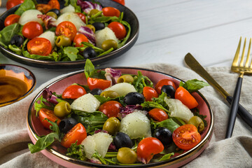 Two servings of salad with melon, tomatoes and olives