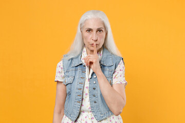 Secret elderly gray-haired female woman in dress denim waistcoat posing looking camera saying hush...