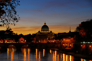 Beautiful sunset view of Rome along River Tiber with the iconic St Peter illuminated
