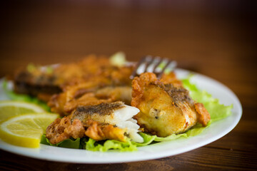 fried hake fish in batter with lettuce and lemon in a plate
