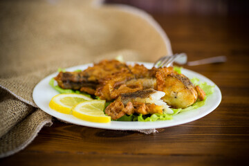 fried hake fish in batter with lettuce and lemon in a plate
