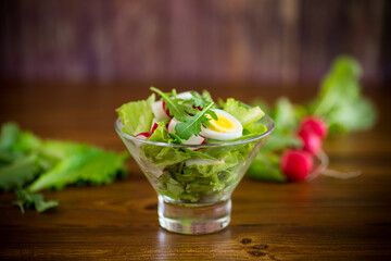 spring salad with arugula, boiled eggs, fresh radish, salad leaves in a glass bowl