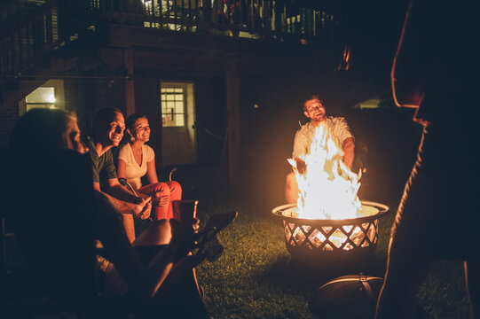 Mid 20s Aged Friends Gathered Around a Campfire During House Party