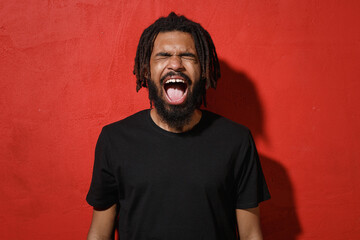 Frustrated crazy young african american man guy with dreadlocks 20s wearing black casual t-shirt...