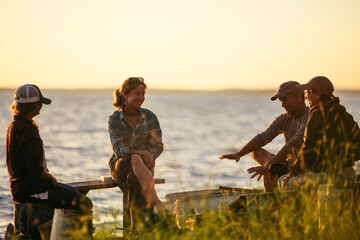 Family Sitting Around a Lakeside Campfire During Sunset
