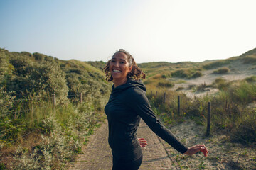 Young woman tunes around during her workout in the dunes