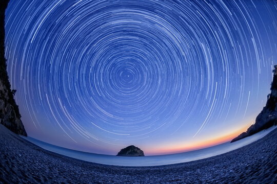 Star trails over the northern sky on a beach.