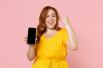 Happy young redhead plus size body positive female woman in yellow dress hold mobile phone with...