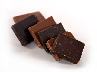 Chocolate cubes, milk and dark, bitter chocolate bar pieces on white background, close-up view.