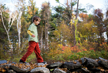 Boy walks on old stone wall in a forest in autumn