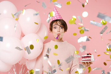 Amazed young woman in casual sweater birthday hat isolated on pastel pink background. Birthday...