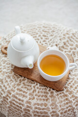 A mug of hot tea, a teapot, a wooden stand on an ottoman. Cozy autumn. Winter breakfast. Cotton.