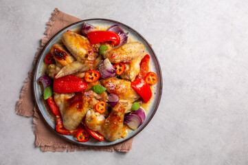 Baked chicken wings marinated in orange jam, with bell peppers, hot peppers and red onions.