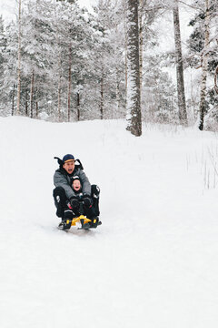 Father and Son Riding Sled Down Hill