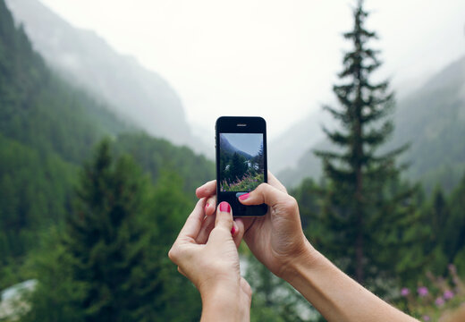 Woman taking a photo up in the mountains with her phone.