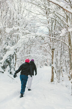 Two Women on Snowy Path in Forest