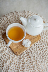 A mug of hot tea, a teapot, a wooden stand on an ottoman. Cozy autumn. Winter breakfast. Cotton.