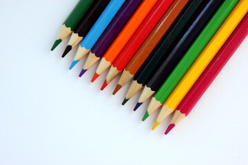 Fototapeta premium Colored pencils on white background. Many different colored pencils. Color pencil. Pencils are sharp. Pencils placed diagonally in the upper-right corner. Close-up. Copy space. Background. Flatlay