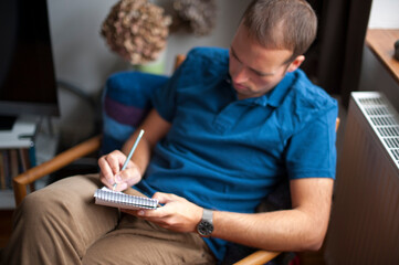 seated man writing in a notepad