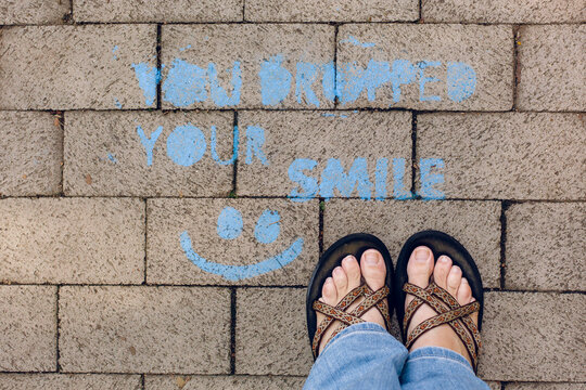 Looking down on sidewalk grafiti next to a woman's feet.