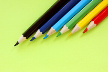 Colored pencils on a green background. Lots of different colored pencils. Colorful pencil. Close. Pencils are sharp. Pencils lie diagonally in the upper right corner. Copy space. Background. Fiat lay.