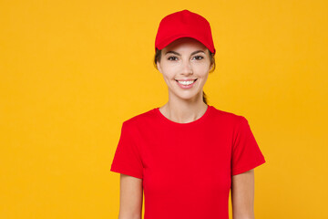 Delivery employee woman in red cap blank t-shirt uniform workwear work courier in service during quarantine coronavirus covid-19 virus, posing look camera isolated on yellow background studio portrait