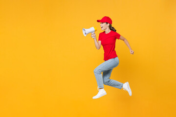 Fototapeta na wymiar Full length body fun delivery employee woman in red cap blank t-shirt uniform work courier in service jumping scream in megaphone announces discounts sale hurry up isolated on yellow background studio