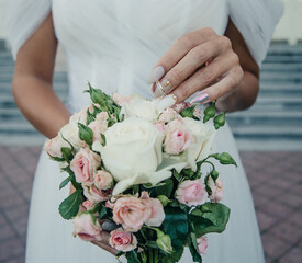 bride's hand with an elegant wedding ring with white gold diamonds on a bouquet of their peonies