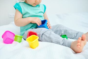 Caucasian toddler playing with colorful toys on the bed