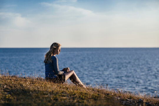 Woman sitting by the sea at sunset