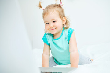 Fototapeta premium Caucasian toddler smiling and looking into laptop