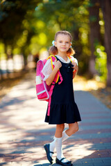 Beautiful little girl with backpack walking in the park ready back to school, fall outdoors, education concept.