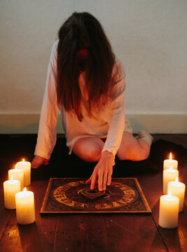 Woman Using A Ouija Board Surrounded By Candles