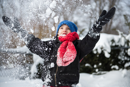 Boy throws freshly fallen snow into the air with joy