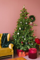 Christmas tree in pink living room style. Vintage yellow sofa with turquoise plaid and maroon velvet banquette. Christmas background.