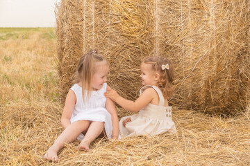 two girls hugging sitting on the hay.
