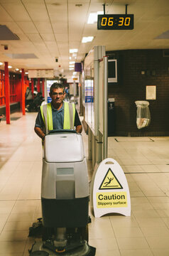 Worker cleaning floor with a scrubber dryer.