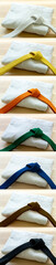 Martial arts colored belts and uniforms on a wood background.