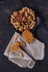 Peanut butter on bread, peanut sandwich, nuts scattered on the table on a plate. Dark background....